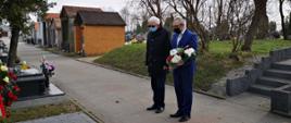 Starosta Krzysztof Bieńkowski w towarzystwie męża śp. senator Janiny Fetlińskiej - Włodzimierza Fetlińskiego. Zdjęcie przedstawia Starostę Przasnyskiego w chwili zadumy na chwilę przed złożeniem kwiatów. Cmentarz komunalny w Ciechanowie.