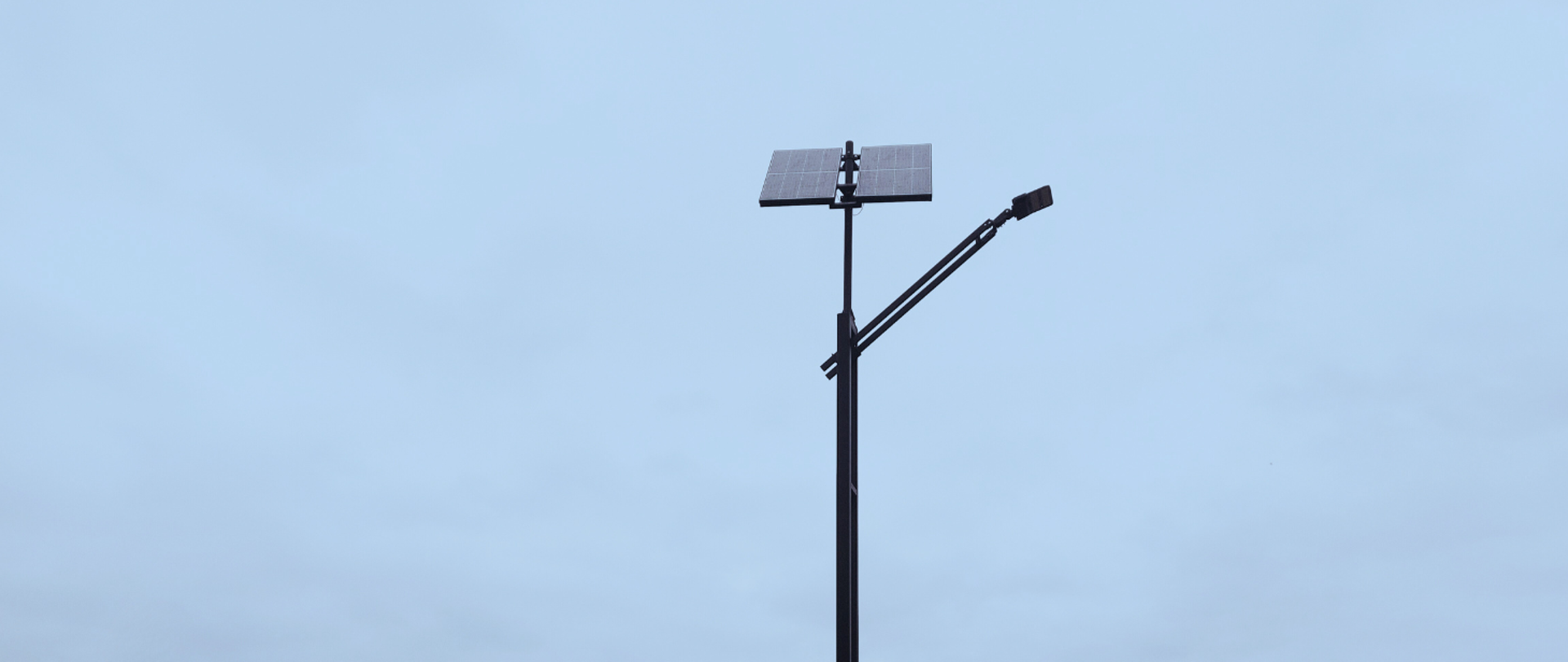 Lampa OZE z panelem fotowoltaicznym na tle niebieskiego nieba