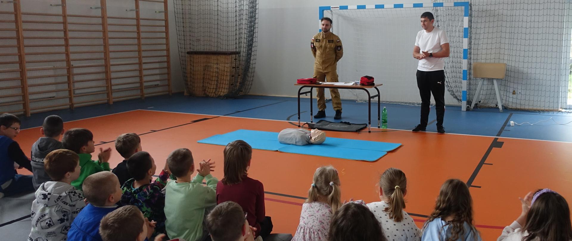 Uczniowie klas I-VIII zebrani na sali gimnastycznej biorą udział w szkoleniu