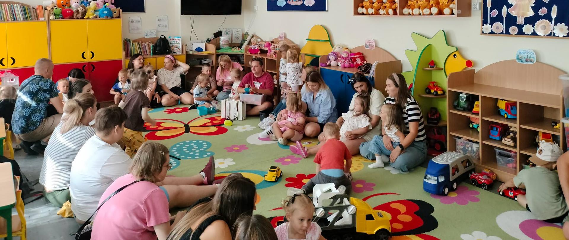 Dzieci z rodzicami siedzą w kole 