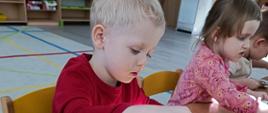 Kreatywne zajęcia artystyczne - dzieci siedzą przy stole, malują wycinanki w kształcie kotów