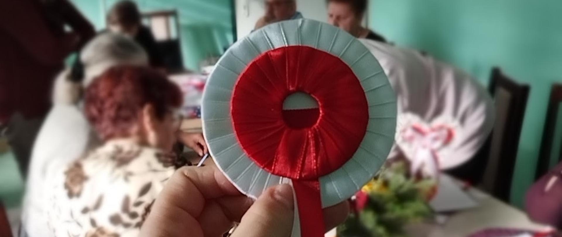 Biało czerwony kotylion z papieru i wstążek.