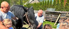 Gospodarze zagrody prowadzą konia w kierunku dzieci