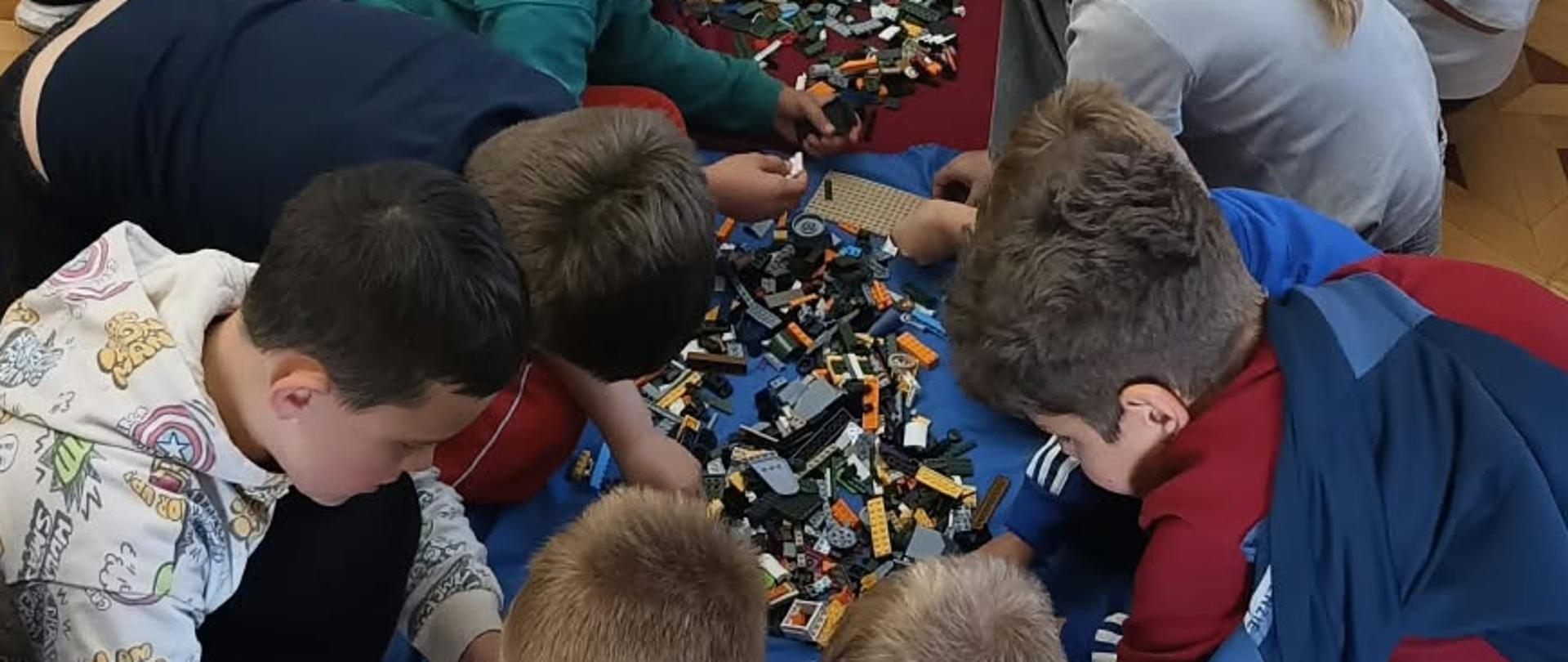 Uczniowie budują modele radia z klocków COBI podczas warsztatów.