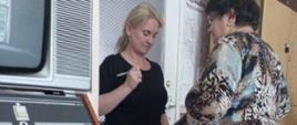 Uczestniczka warsztatów stoi na wadze, obok niej stoi psychodietetyk