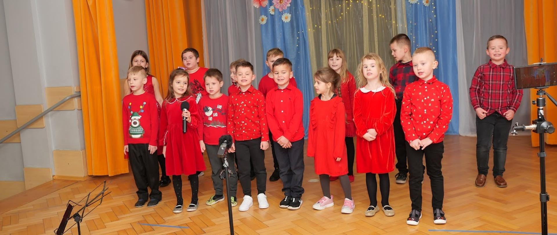 Grupa dzieci stoi na scenie i śpiewa piosenkę.