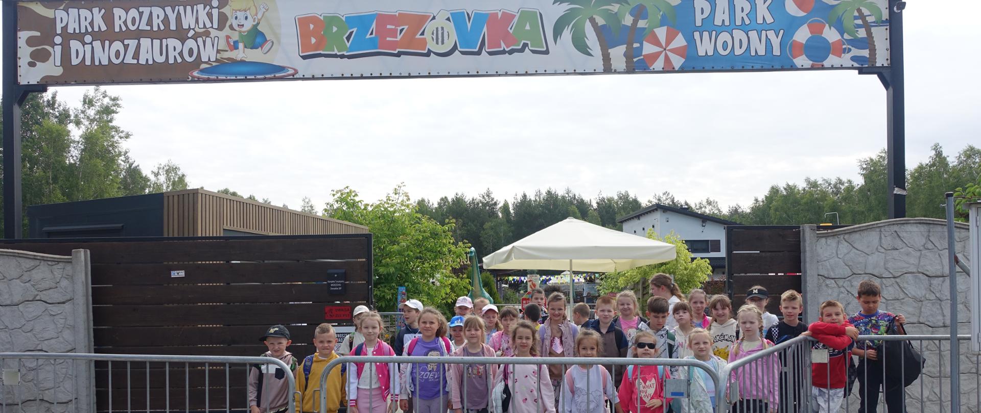 Uczestnicy wycieczki stoją przed wejściem do Parku Rozrywki i Dinozaurów w Brzezówce
