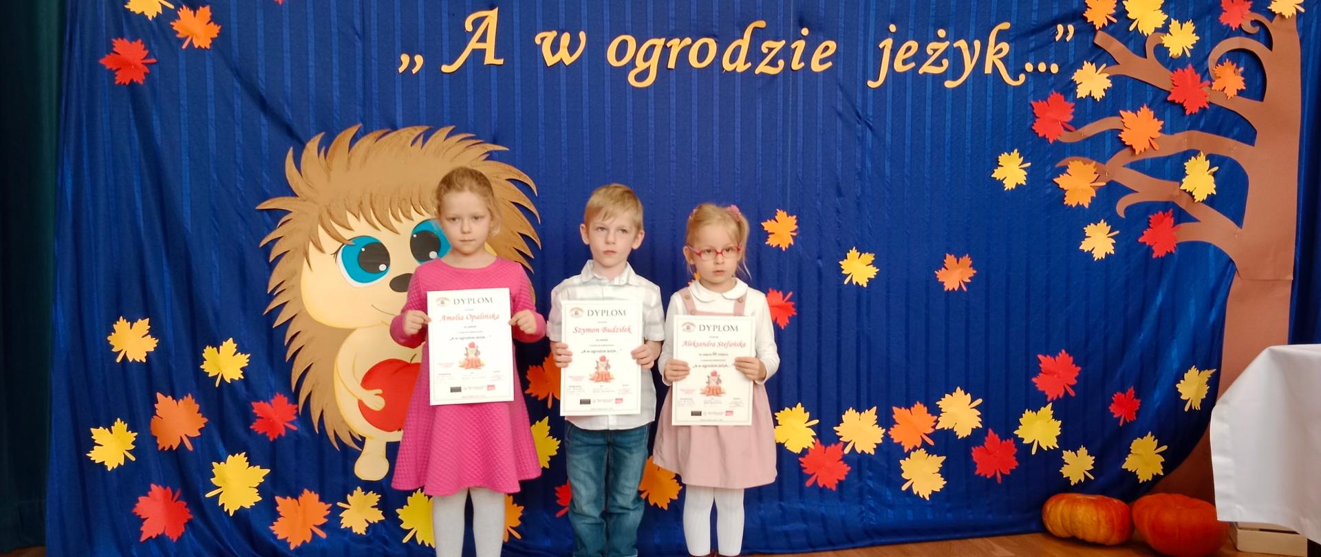 Dzieci na tle dekoracji jesiennej z dyplomami w rękach