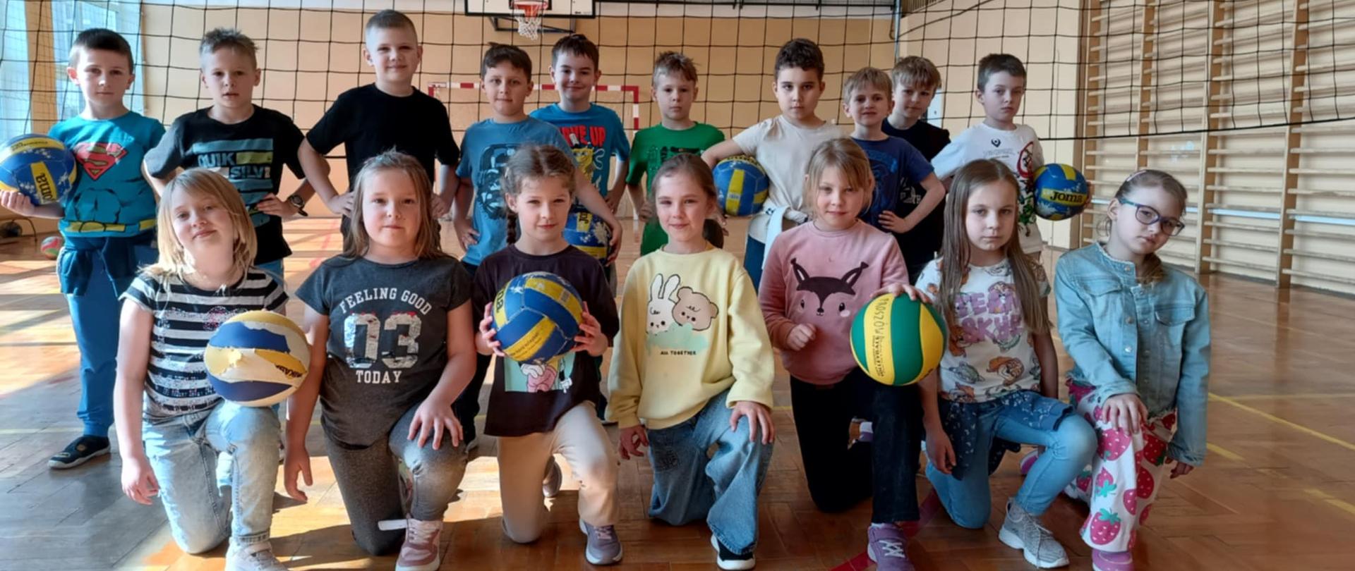 grupa dzieci z piłkami do siatkówk