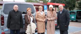 Na zdjęciu widać Starostę Zambrowskiego Edytę Marchelską-Groszfeld oraz Wicestarostę Zambrowskiego Roberta Macieja Rosiaka wraz z trzema innymi osobami, stojących na parkingu. W tle widoczne są samochody i budynek SOSW w Długoborzu.
Okazją do zrobienia zdjęcia było uroczyste przekazanie nowego mikrobusu dla Specjalnego Ośrodka Szkolno-Wychowawczego w Długoborzu, które odbyło się 30 października 2025 roku. 