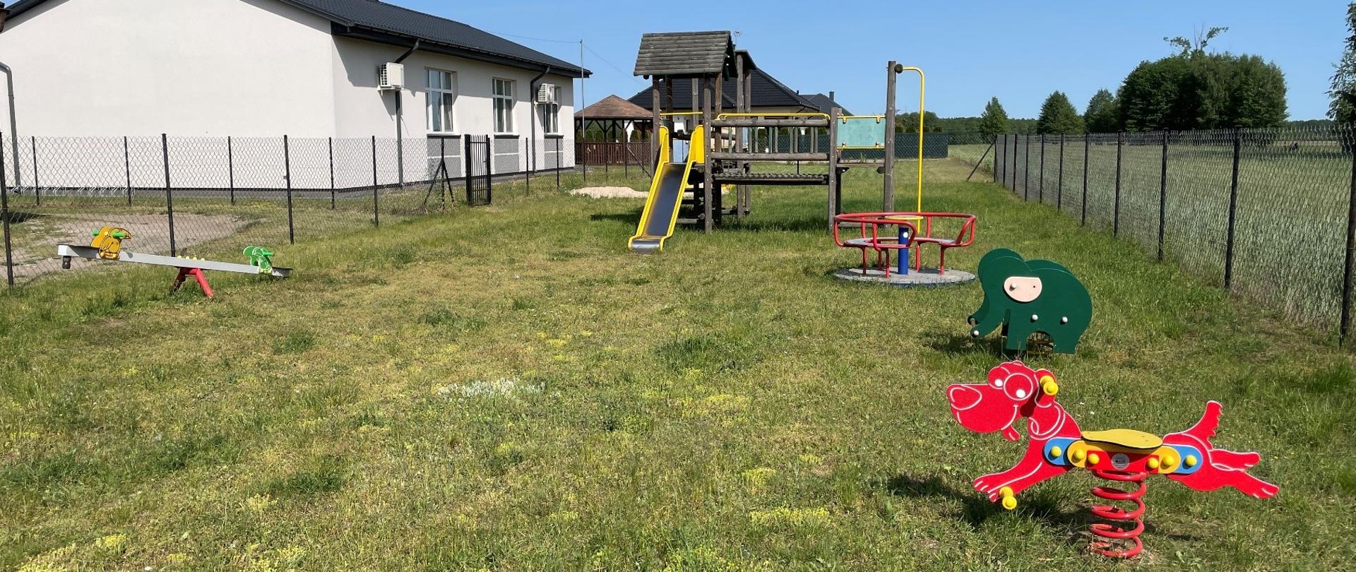 Plac zabaw w miejscowości Udrzynek, w tle świetlica wiejska oraz altana.