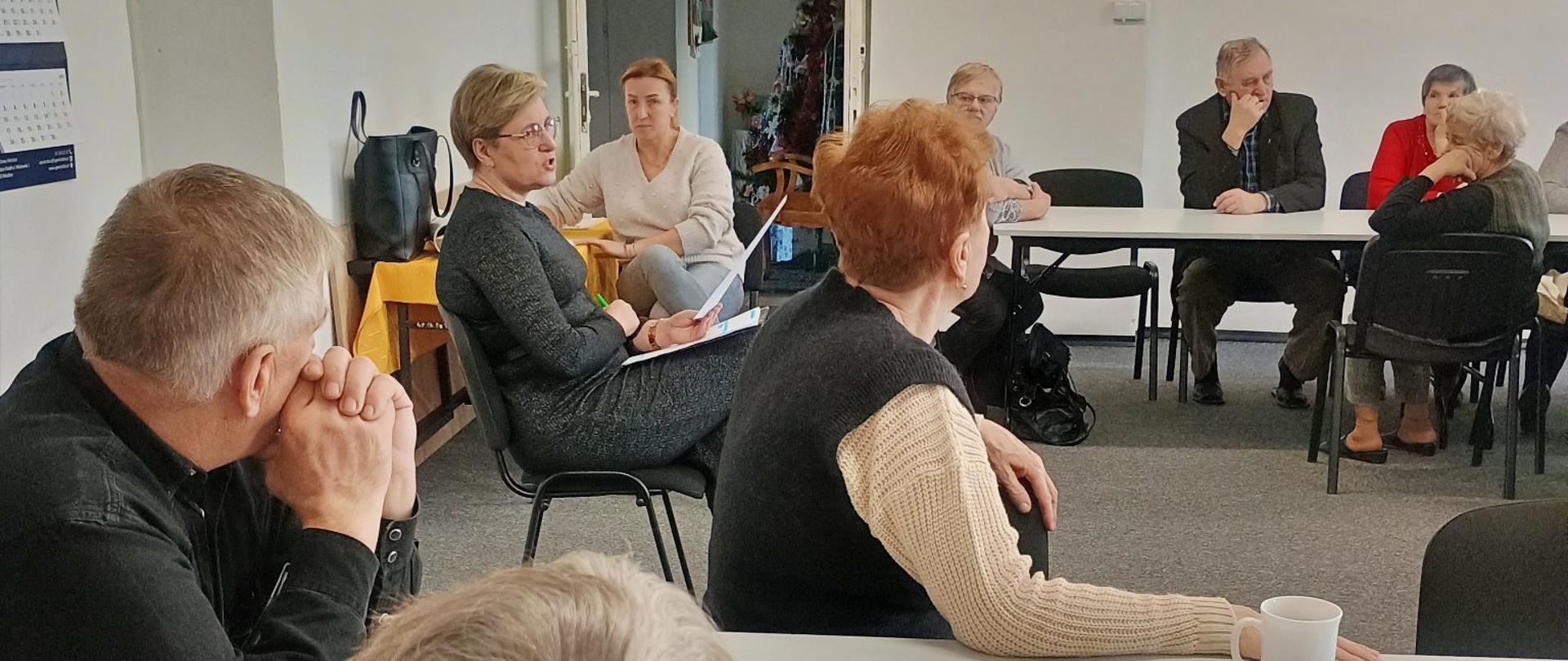 seniorzy podczas spotkania słuchają prelekcji kierownika OPS