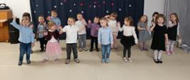 Dzieci w trakcie części artystycznej uroczystości - stoją w rzędzie, recytują i śpiewają.