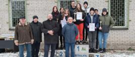 Zdjęcie grupowe organizatorów turnieju za nimi zwycięzcy chłopcy i dziewczęta stoją na podium, prezentują puchary i dyplomy.