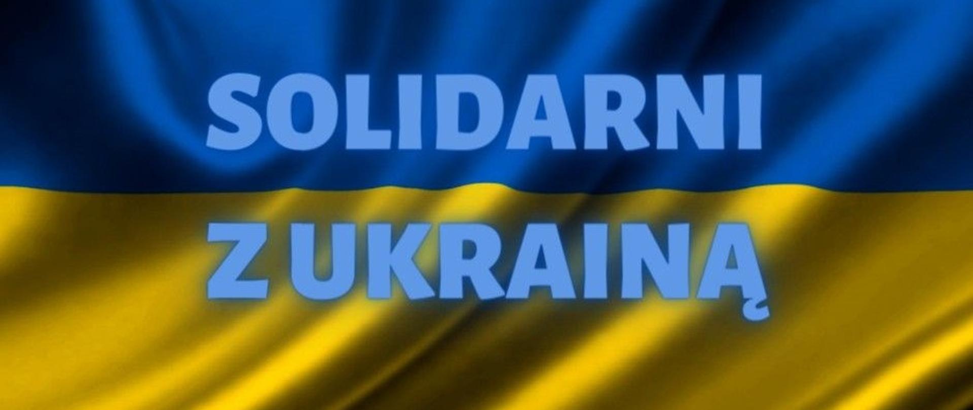 Napis Solidarni z Ukrainą na tle Ukraińskiej flagi