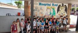 grupa dzieci i dorosłych pozują do zdjęcia na tle muralu 