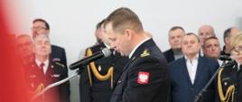 Fotografia wykonana w garażu PSP w Sokołowie Podlaskim podczas uroczystego pożegnania komendanta odchodzącego na emeryturę. Na zdjęciu moment przemówienia komendanta st. bryg. Pawła Dmowskiego w tle widać zaproszonych gości.