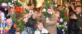 Uczestnicy konkursu na najpiękniejszą i najwyższą Palmę Wielkanocną pozujący do zdjęcia na tle ołtarza w kościele parafialnym