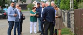 9 osób mężczyźni i kobiety stojący przy drodze. 