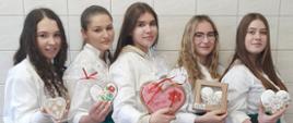 Na zdjęciu grupa dziewcząt w pracowni cukierniczej prezentująca ręcznie zdobione pierniczki