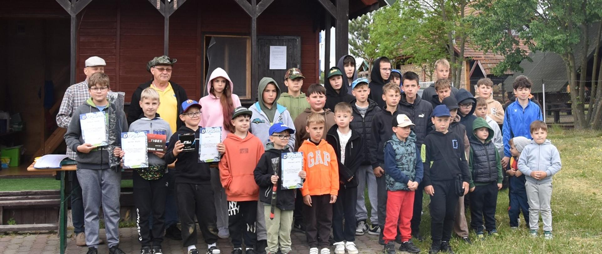 dzieci i młodzież wraz z dwójką dorosłych pozują do wspólnego zdjęcia 