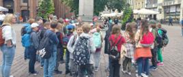 Dzieci ustawione na rynku wokół pomnika Mikołaja Kopernika