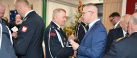mężczyźni w garniturach przełamują się opłatkiem 