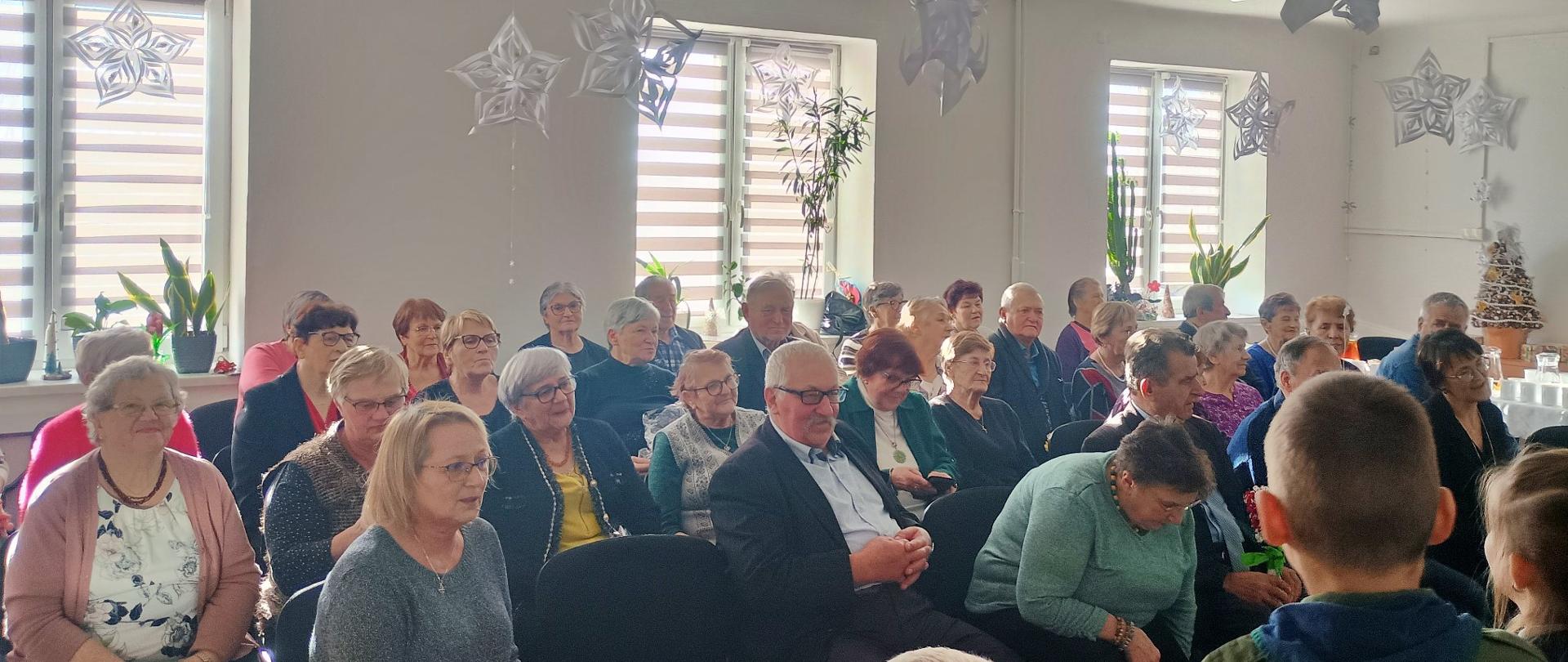 grupa seniorów ogląda przedstawienie przygotowane przez drużynę zuchów