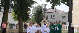 Księża i ministranci w drodze do powitania korowodu