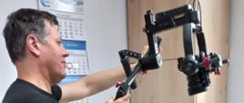 Nagrania - nad siedzącą przed biurkiem kobietą stoi operator kamery