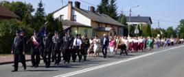zdj.1 - obrazuje barwny korowód, tworzący się na parkingu przed budynkiem Urzędu Gminy w Rudzie Malenieckiej. Na zdjęciu widoczne delegacje z poszczególnych sołectw prezentujące swe wieńce. Delegacje złożone z Pań i Panów odświętnie, folklorystycznie ubranych. Na czele przedstawiciele lokalnego samorządu z Wójtem Gminy na czele niosącym bochen chleba, obok Przewodniczący Rady Gminy oraz Wiceprzewodniczący.