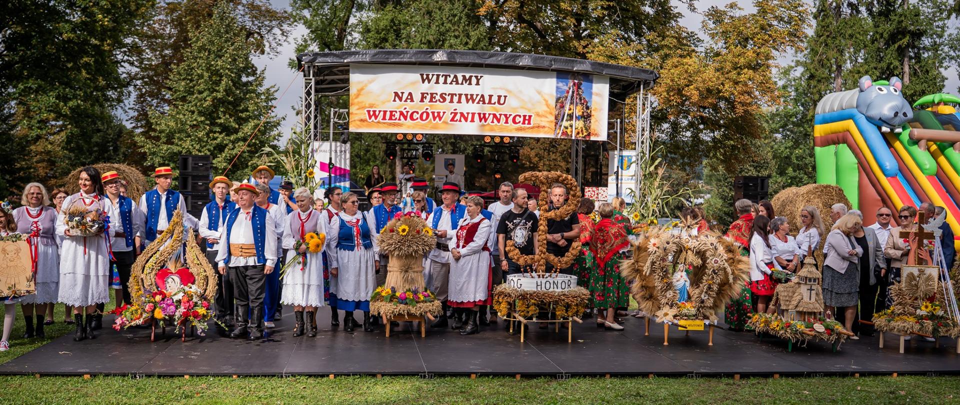 Uczestnicy Festiwalu Wieńców Żniwnych – przedstawiciele lokalnych Kół Gospodyń Wiejskich oraz innych grup – prezentowali swoje misternie wykonane wieńce żniwne. Każda grupa, z dumą prezentując swoją pracę, ukazywała unikalne wzory i kompozycje, od tradycyjnych plecionek po artystyczne interpretacje tematu, tworząc barwną i radosną mozaikę regionalnej kultury i plonów
