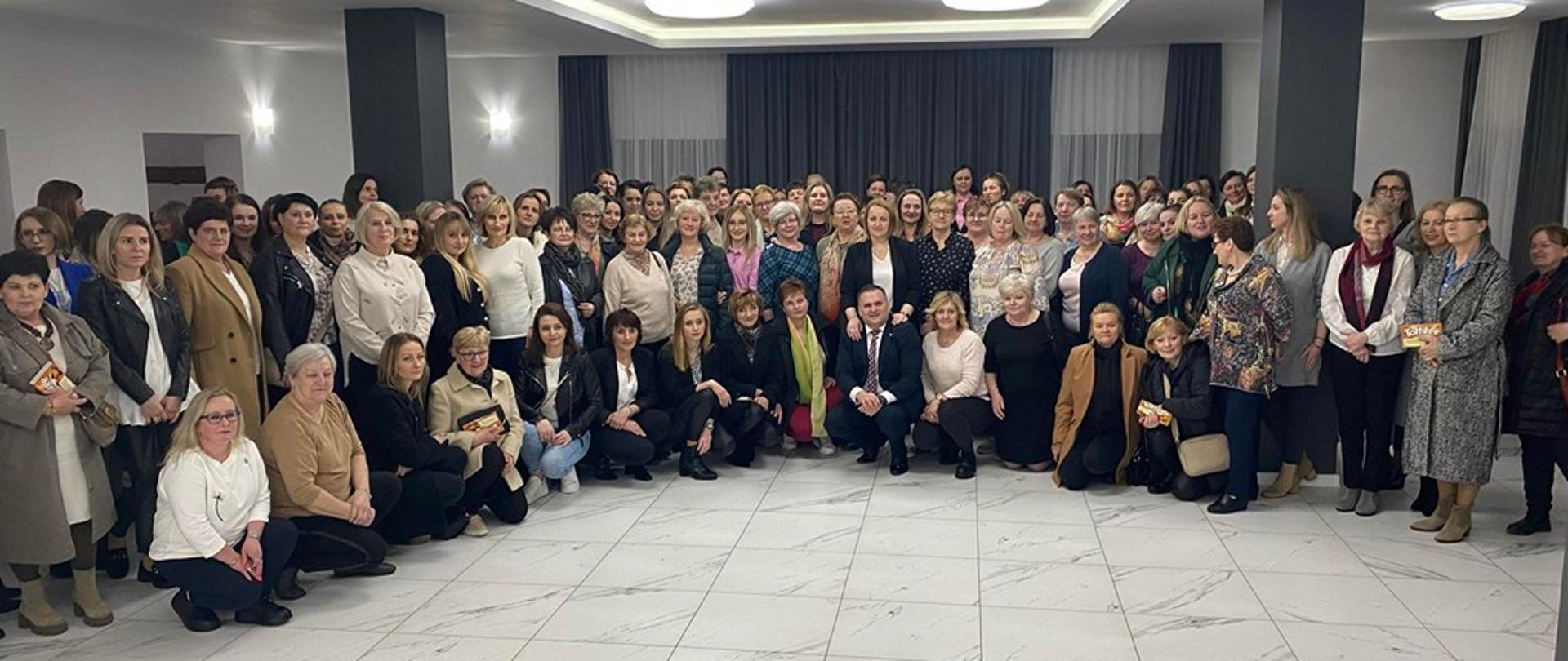 Zdjęcie przedstawia uczestniczki wyjazdu z okazji Dnia Kobiet ok. 140 kobiet pozujące do grupowego zdjęcia z p. Wójtem.