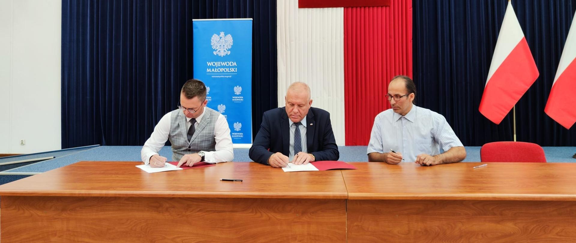 zdjęcie przedstawia od lewej Wójta Gminy Wietrzychowice, wicewojewodę małopolskiego oraz skarbnika gminy Wietrzychowice w trakcie podpisywania umowy
