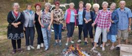 członkowie klubu senior+, piekący kiełbaski nad ogniskiem oraz pozujący do wspólnego zdjęcia