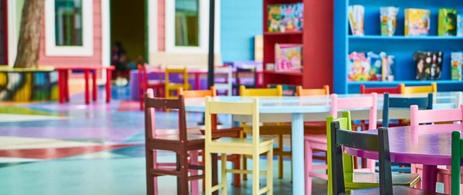 Sala przedszkolna z krzesełkami, stolikami i szafkami