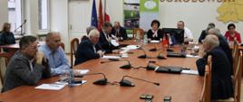 Widok na salę konferencyjną Starostwa Powiatowego. Na pierwszy, planie prostopadle do kadru drewniany, podłużny stół przy którym siedzą radni Rady Powiatu Sokołowskiego, w drugim planie stojący równolegle do kadru stół prezydialny, przy którym siedzą Starosta oraz Wicestarosta Sokołowski, Przewodniczący Rady Powiatu Sokołowskiego wraz z Przewodniczącymi.