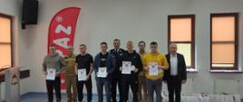 Fotografia grupowa wykonana w siedzibie PSP w Sokołowie Podlaskim, na zdjęciu nagrodzeni uczestnicy, trzymają w dłoniach dyplomy, oraz przedstawiciele Straży Pożarnej i Starostwa Powiatowego w Sokołowie Podlaskim.