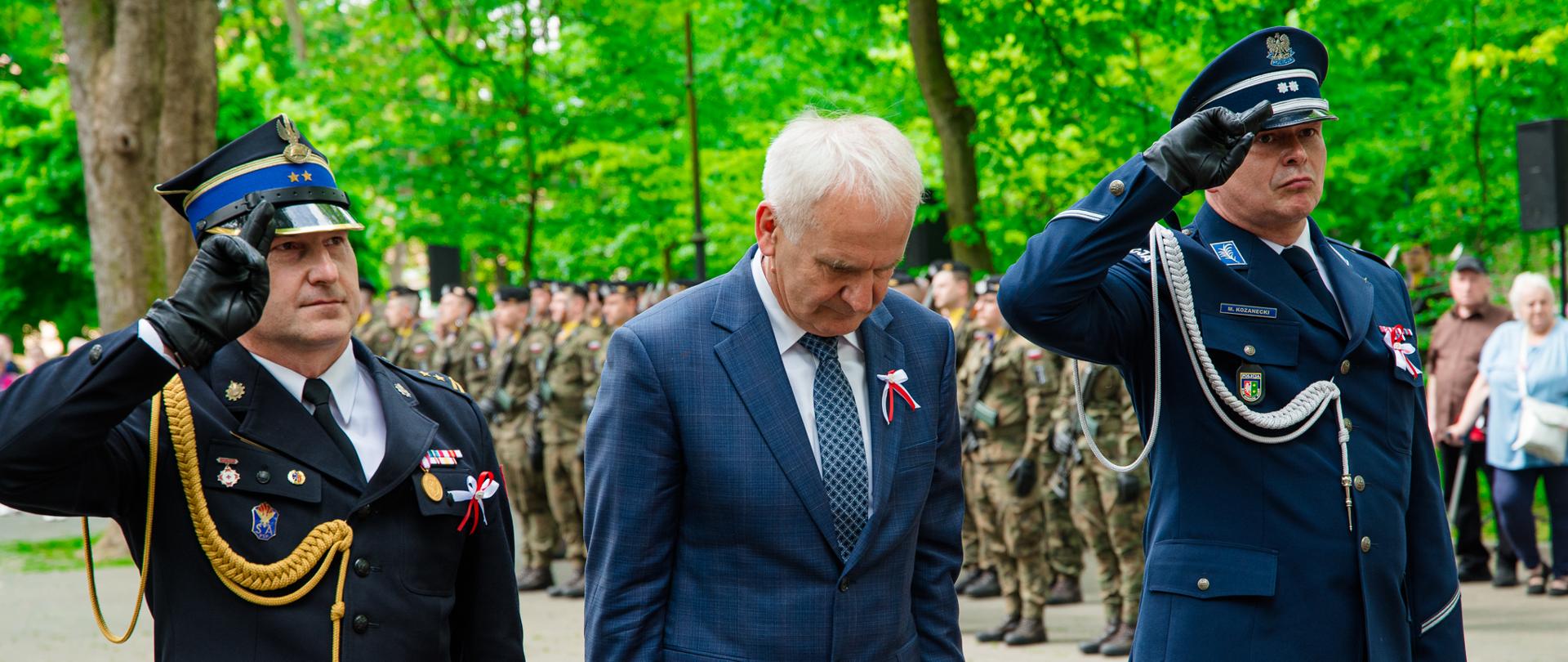 grupa ludzi składająca kwiaty pod pomnikiem