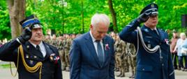 grupa ludzi sladajaca kwiaty pod pomnikiem
