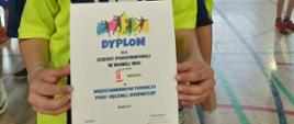 Kapitan drużyny dziewczyn trzyma w ręku dyplom za zajęcie 2 miejsca, za nią stoją w rzędzie członkinie drużyny