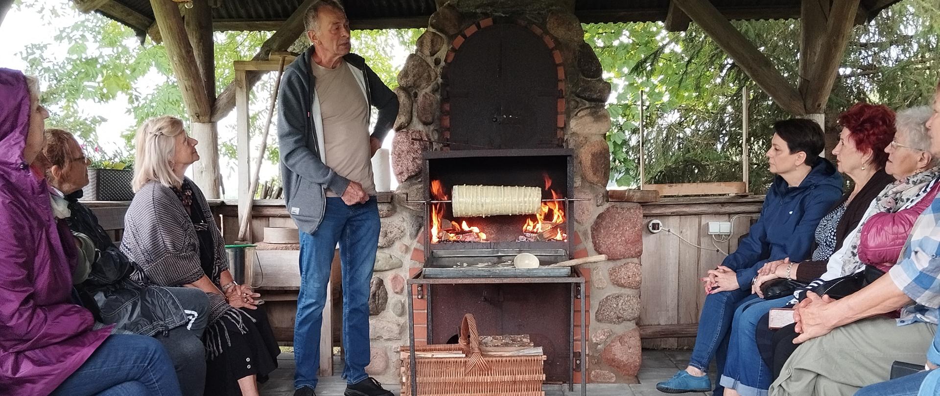 Członkowie klubu senior+ na pokazie wypiekania sękacza nad ogniem
