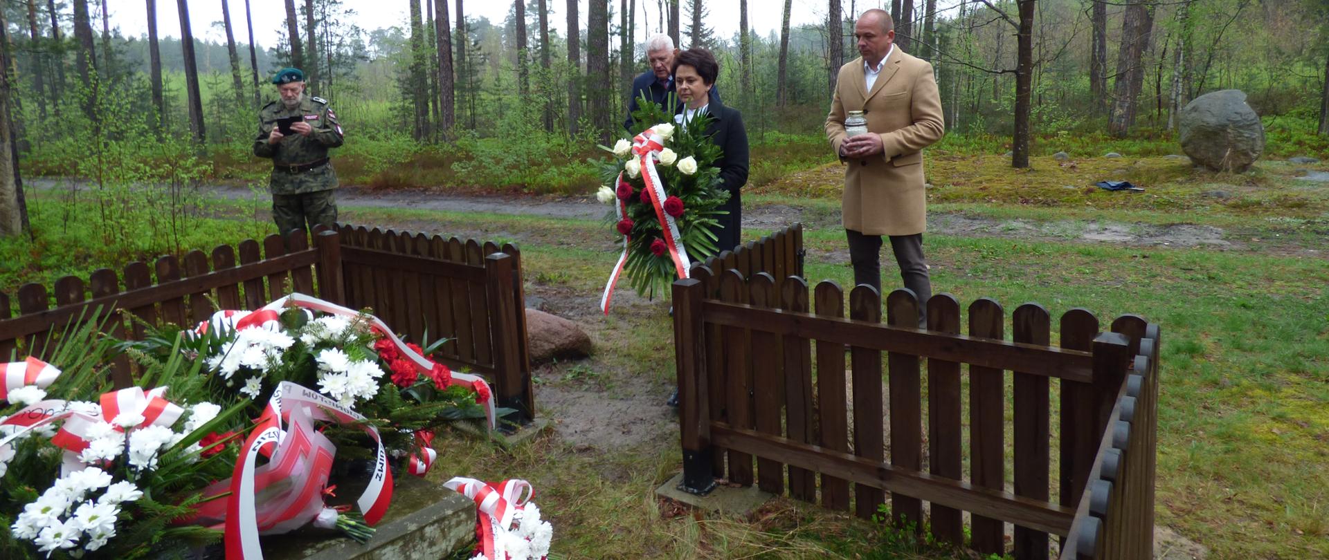 Zdjęcie przedstawia uroczyste złożenie wiązanki patriotycznej oraz zapalenie zniczy biało-czerwonych przez przedstawicieli lokalnego samorządu z Wójtem na czele oraz Przewodniczącym Rady Gminy Ruda Maleniecka i Wiceprzewodniczącym, na mogile Powstańców Styczniowych.