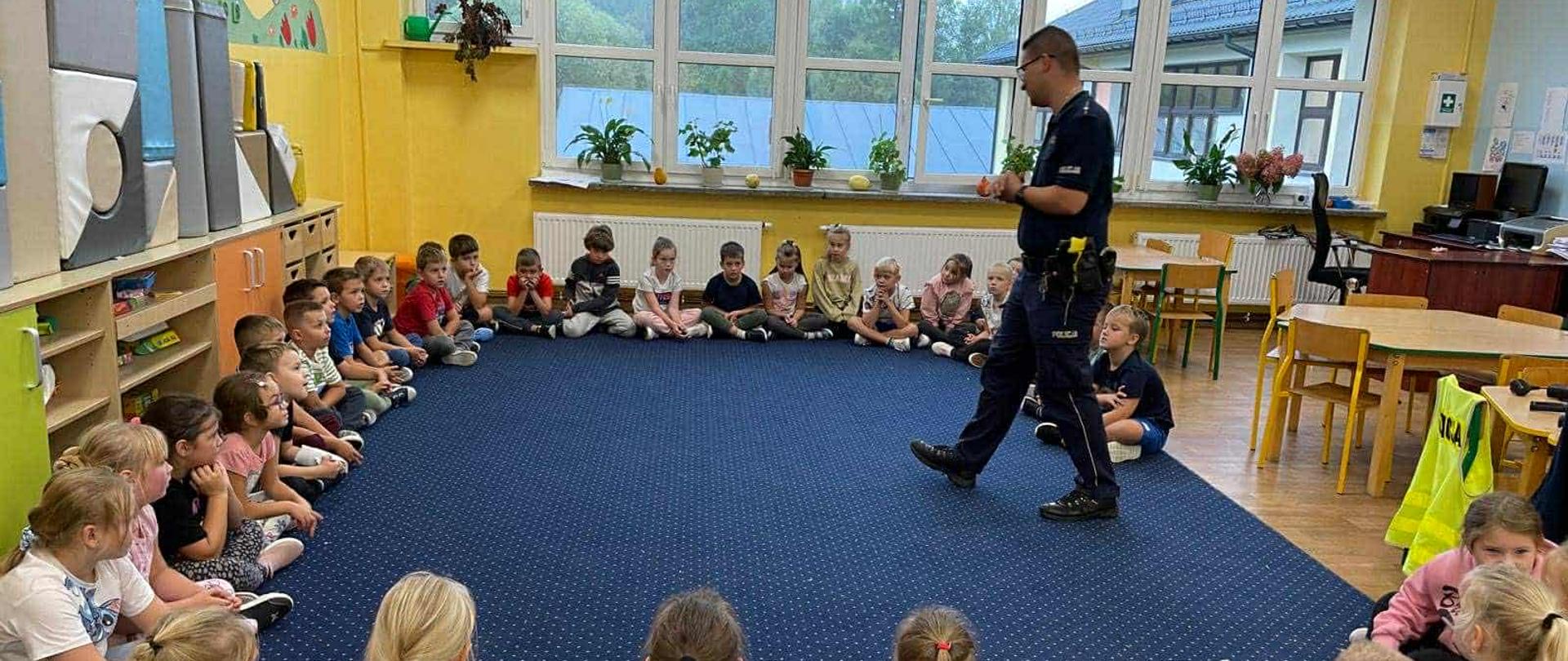 Spotkanie dziec z policjantem dotyczące bezpieczeństwa na drodze.