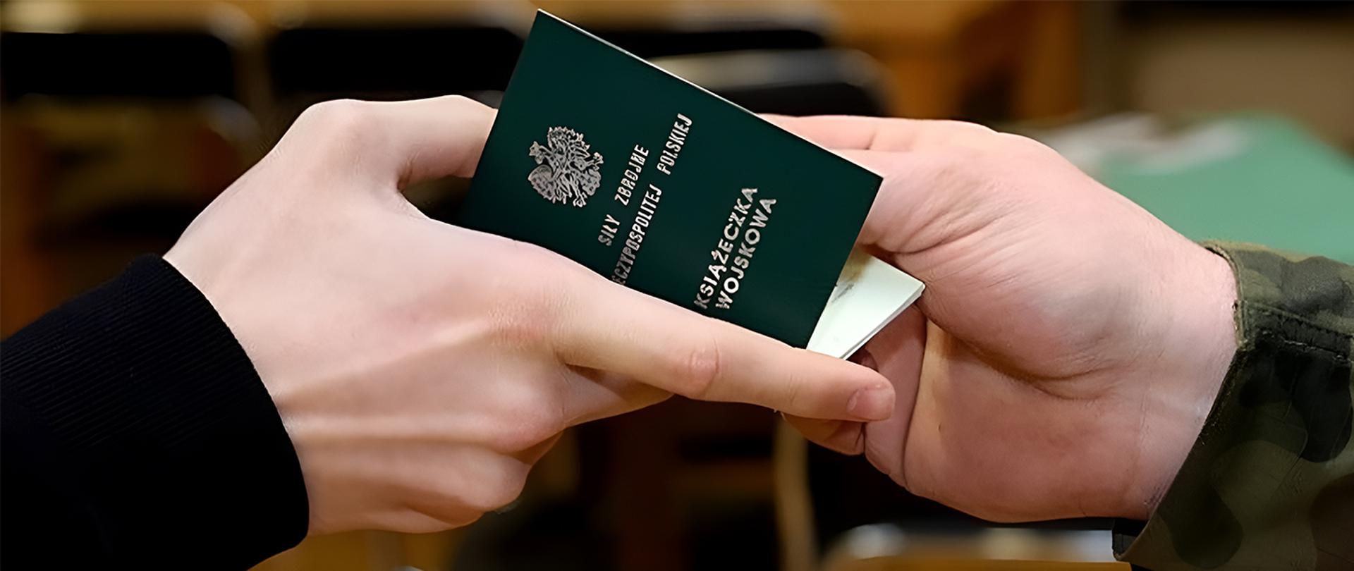 Ręce przekazujące sobie zieloną książeczkę wojskową