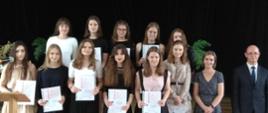 Na zdjęciu dyrektor oraz uczniowie ze swoimi świadectwami z czerwonym paskiem