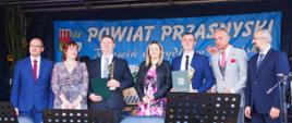 Wręczenie nagród dla najlepszych rolników w powiecie przasnyskim. Na scenie dożynkowej stoją samorządowcy Starosta Przasnyski, Wójt Gminy Jednorożec Krzysztof Iwulski i Senator Jana Maria Jackowski wraz z nagrodzonymi rolnikami z terenu gminy Jednorożec.