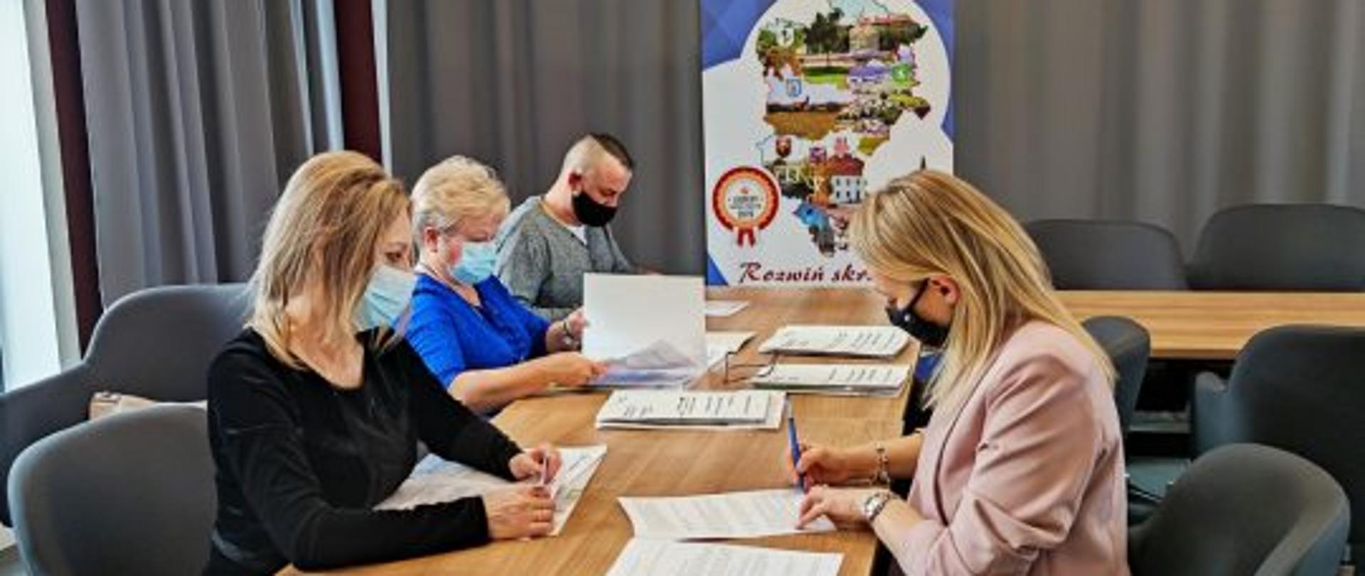Zdjęcie przedstawia nowych przedsiębiorców w trakcie podpisywania umów na dofinansowanie działalności gospodarczej. Sala konferencyjna w Centrum Aktywizacji Biznesu Starostwa Powiatowego w Przasnyszu.