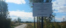 Tablica informacyjna dotycząca modernizacji dróg dojazdowych do gruntów rolnych współfinansowanej ze środków Województwa Małopolskiego, ustawiona przy nowej drodze.
