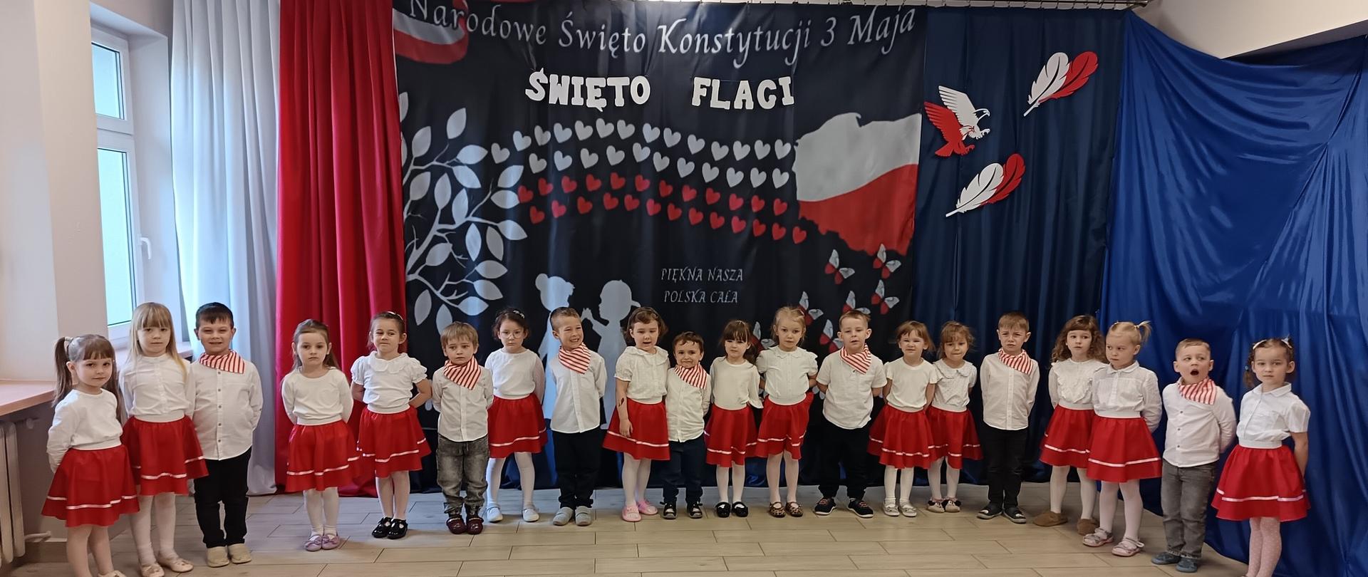Dzieci w strojach galowych , za nimi napis Święto Flagi